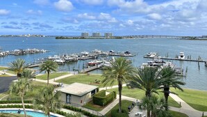 A marina with boats docked, a clear sky, and a view of distant buildings.
