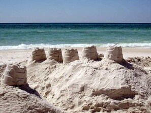 Una playa arenosa con una hilera de castillos de arena.