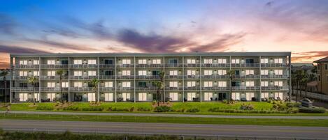 A multi-story hotel with balconies, a well-maintained lawn, and a clear view of the road in the foreground.