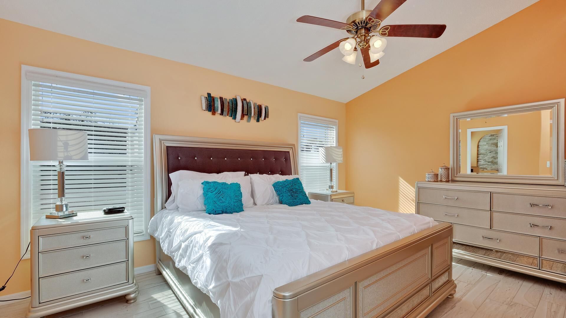 A bedroom with a large bed, a ceiling fan, and a dresser.