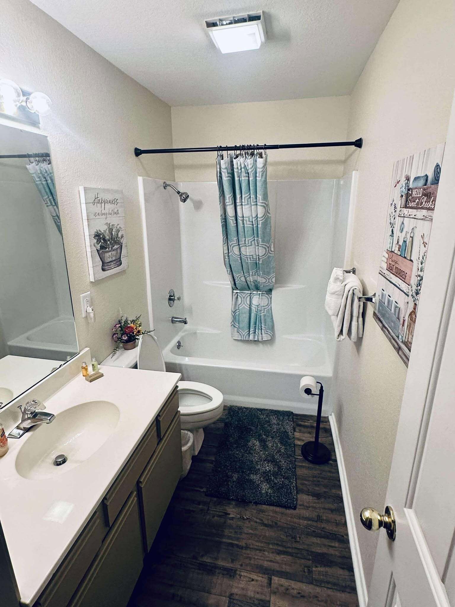 A bathroom with a white sink, toilet, and bathtub. There is a shower curtain, a towel rack, and a mirror.