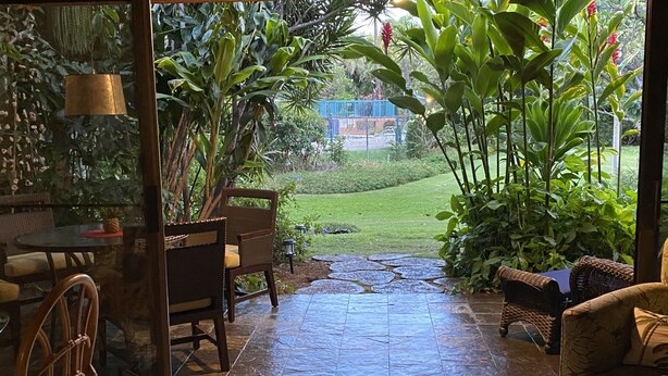 An indoor/outdoor patio area with a stone pathway leading to a grassy lawn.