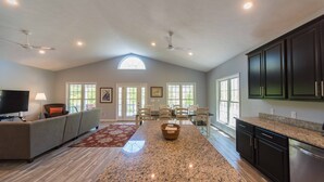 A spacious living area with a large granite island, dark wooden cabinets, and a television on a stand. - Built in 2017 - 4 BR/3 BA Lakeview in Grand Rivers - The Only City on Both Lakes (Grand Rivers)