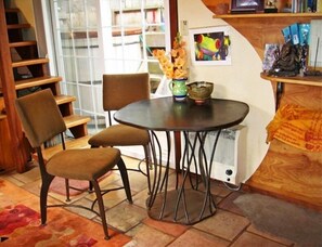 Relax in this inviting room with a round table, two comfortable chairs, and a bookshelf filled with books and decorative items.