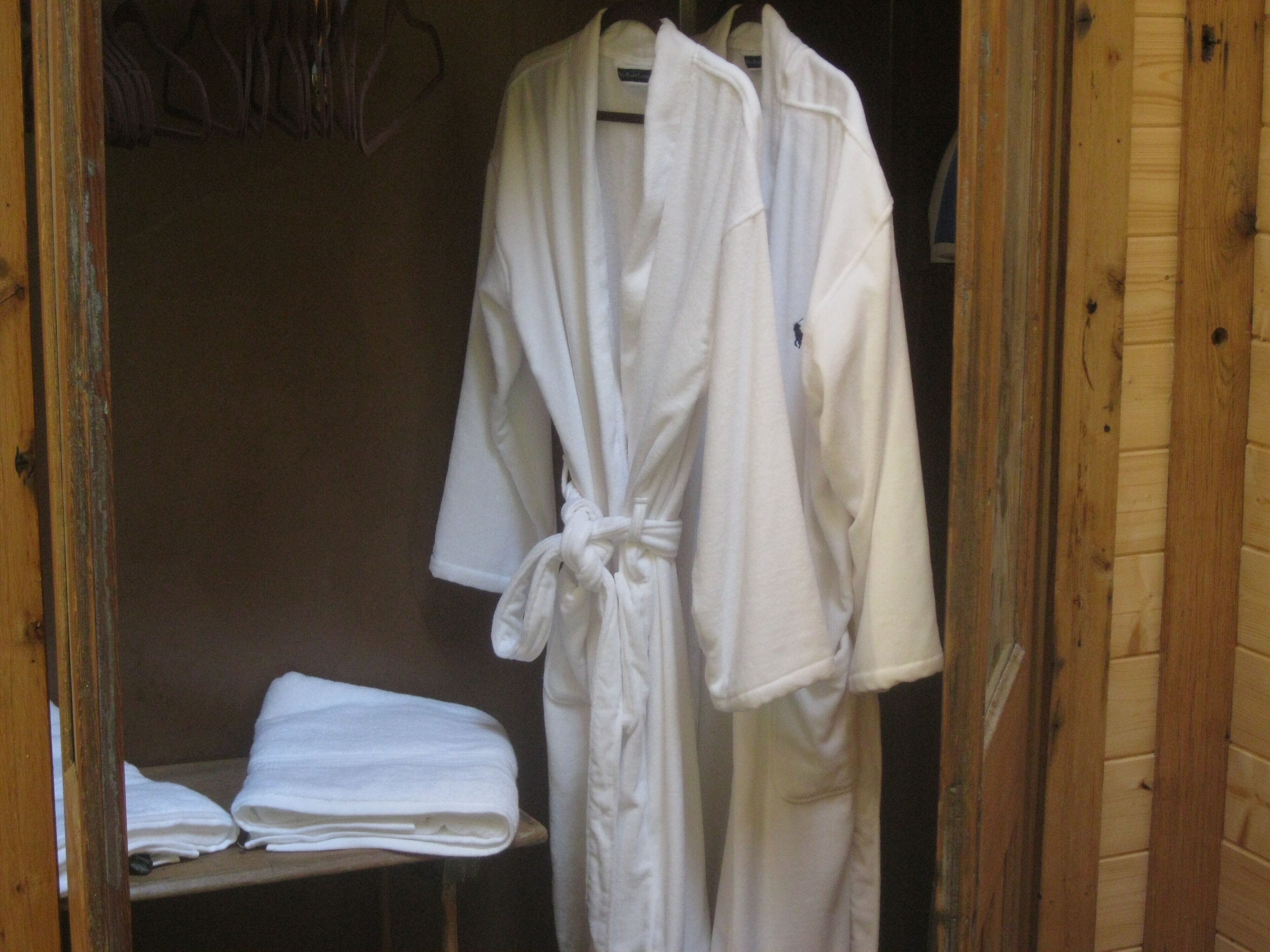 A wooden interior with a wooden bench and a white robe hanging on a rack.