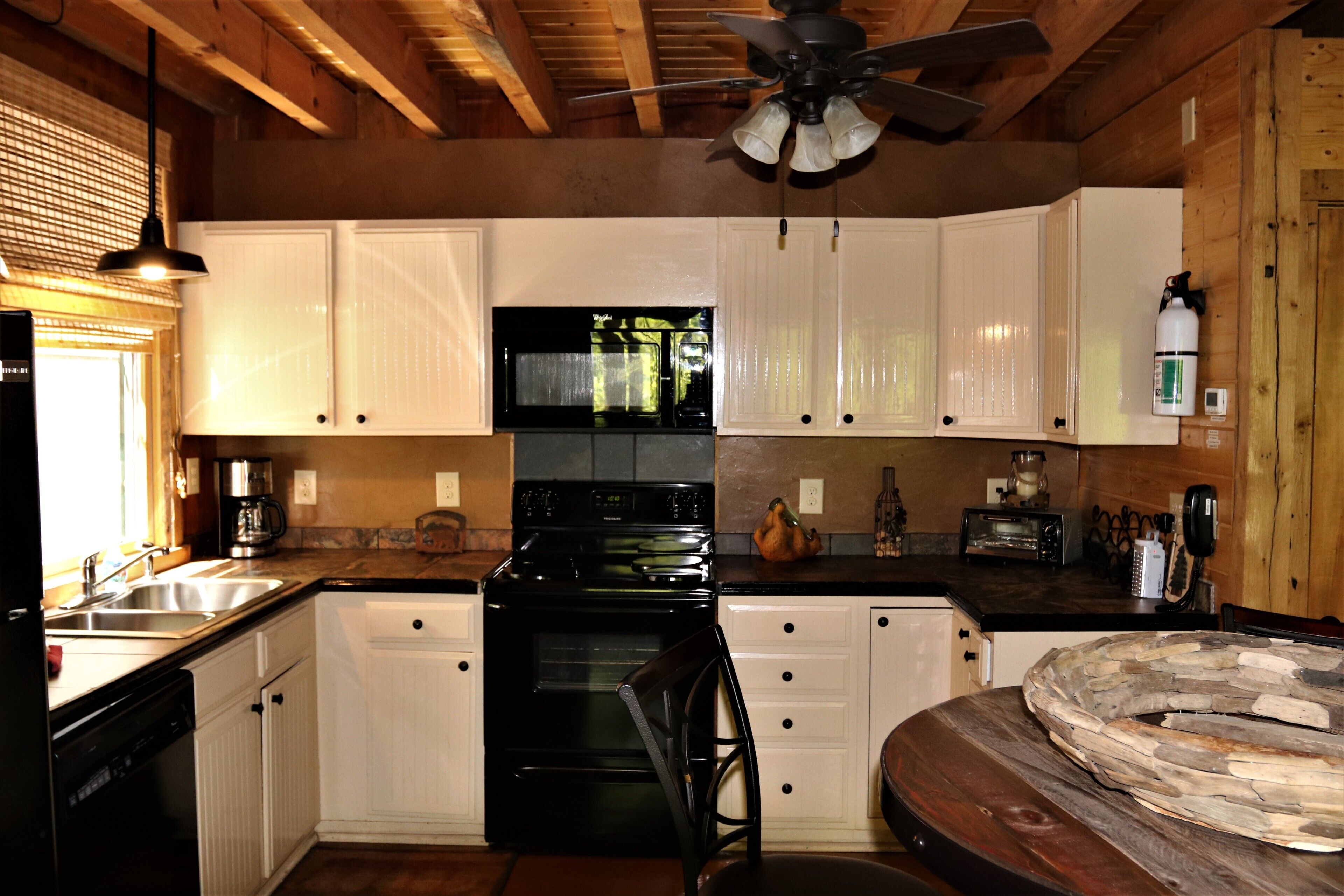 A kitchen with white cabinets, a black stove, and a wooden ceiling.