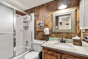 A bathroom with a shower, toilet, sink, and vanity.