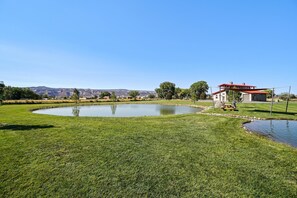 A well-maintained grassy area with a pond and a building with a red roof. - Carriage: Trailside Patio Paradise on 5 Acres (Fruita)