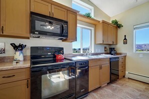 A modern kitchen with wooden cabinets, a stainless steel oven, a microwave, and a dishwasher. - Carriage: Trailside Patio Paradise on 5 Acres (Fruita)