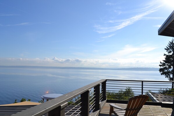 Ein Balkon mit Blick auf das Meer, ein Holzhocker und ein kleiner runder Tisch.