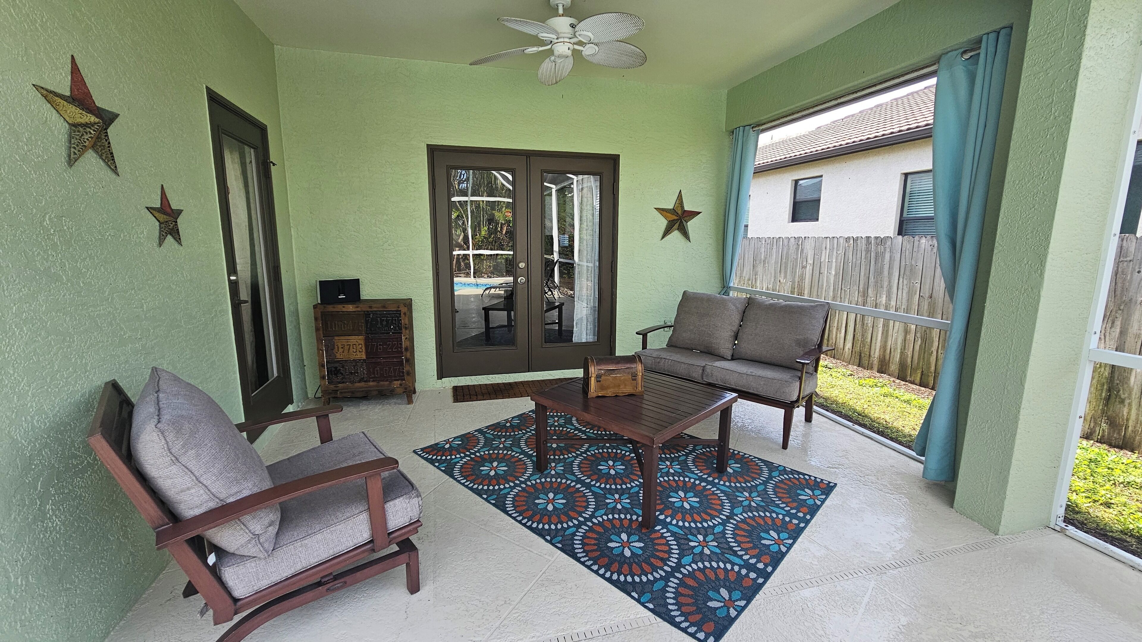A covered patio with a sofa, chairs, a coffee table, and a patterned rug.