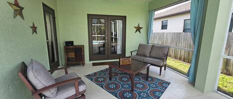 A covered patio with a sofa, chairs, a coffee table, and a patterned rug.