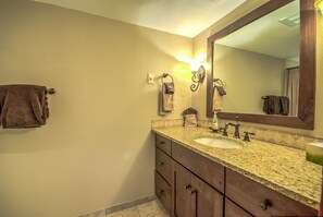 A bathroom with a granite countertop sink, a mirror, and a towel rack.