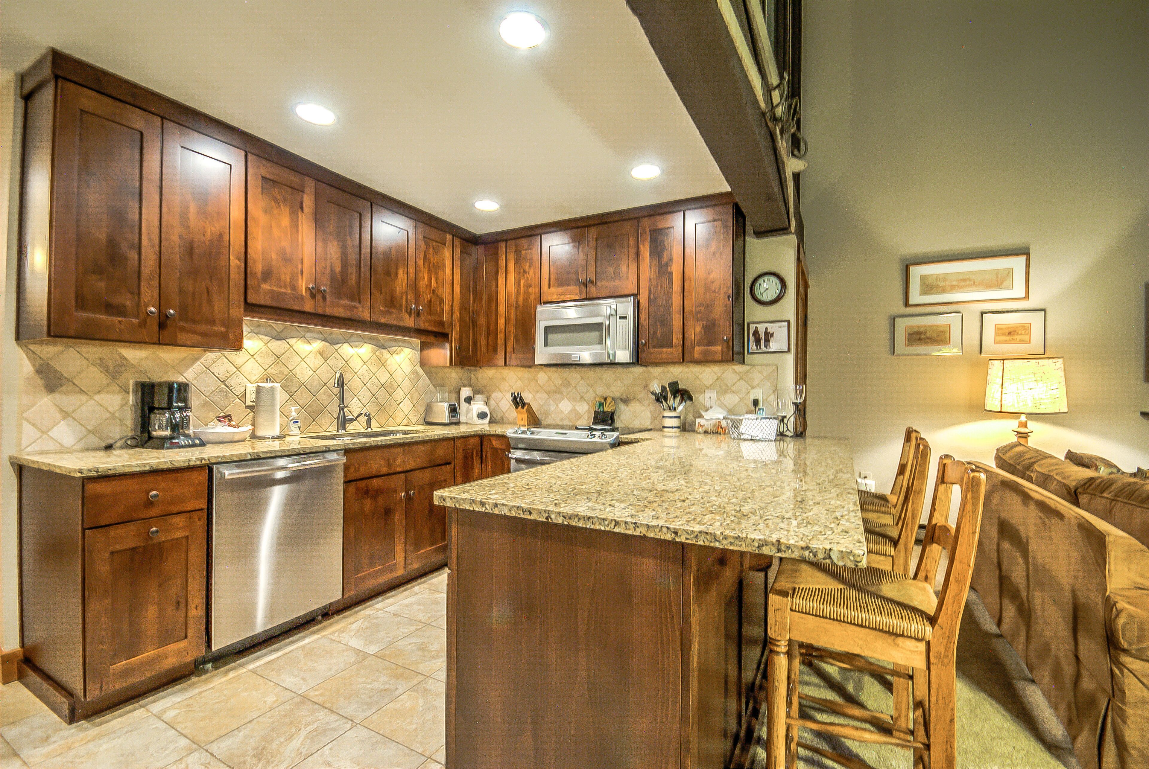 A kitchen with wooden cabinets, a built-in microwave, and a large island with bar stools.