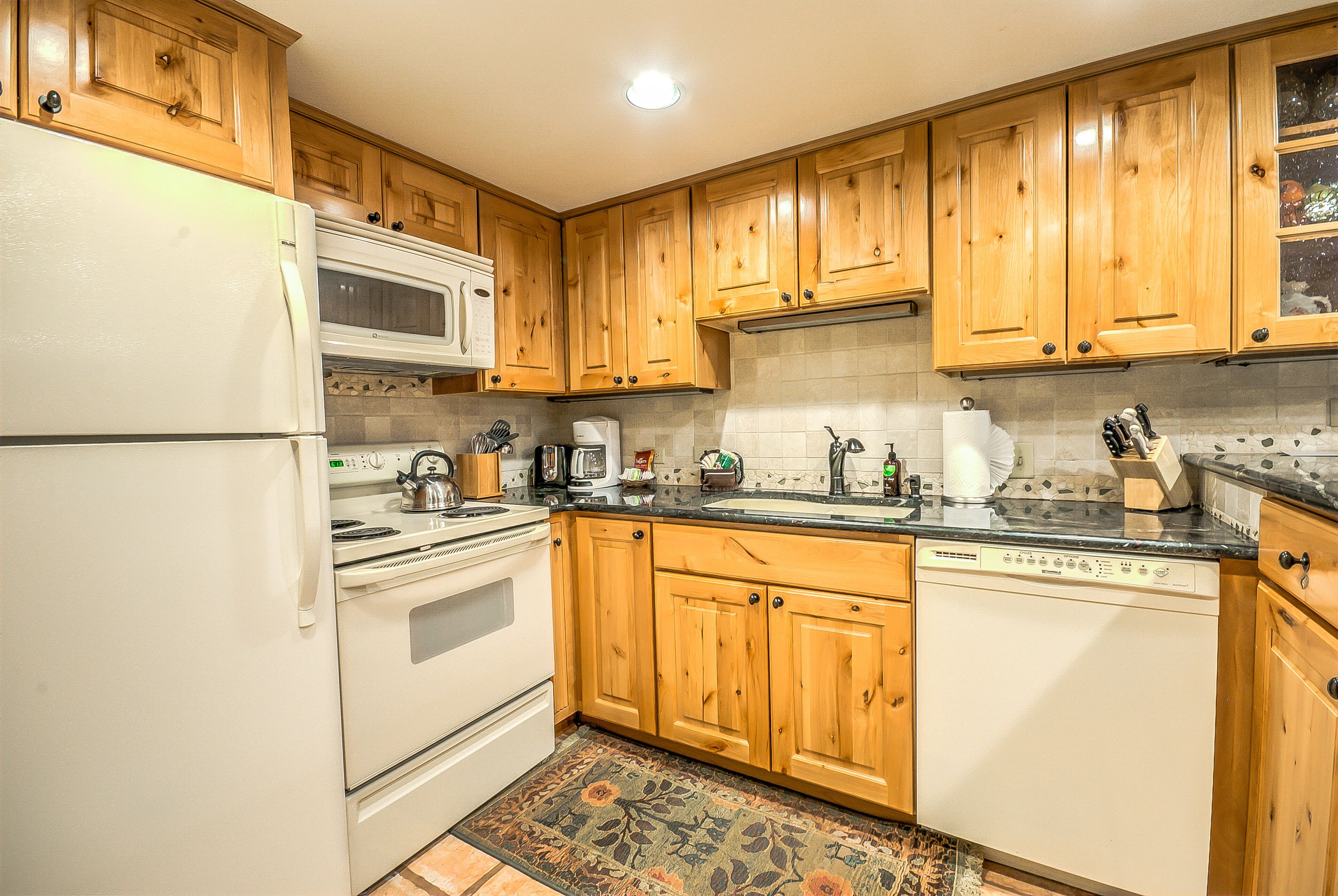 A kitchen with wooden cabinets, a white refrigerator, a stove, and a dishwasher.