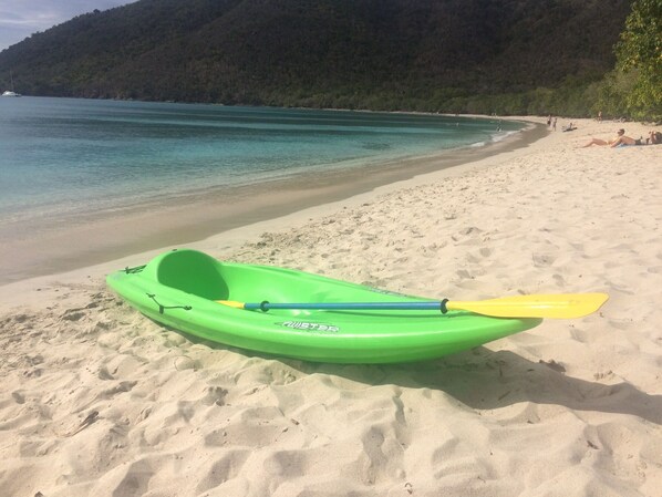 A green kayak with a yellow paddle on a sandy beach with a forested hill in the background. - Couples Retreat, Sweeping VIEWS, Kayaks Await at the Beach! (St. John)