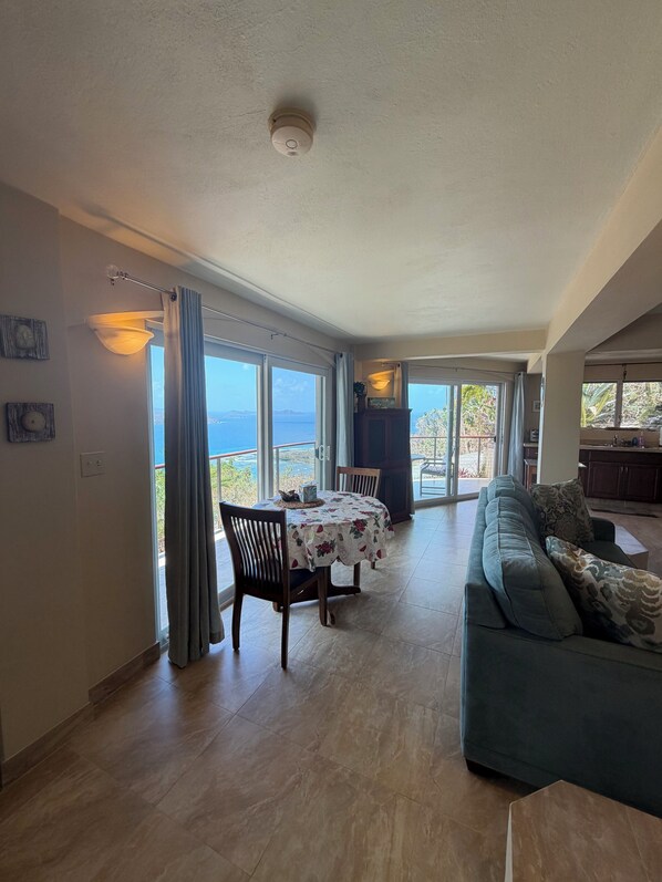 Un vaste espace de vie comprenant une table à manger, un canapé et une vue sur la mer.