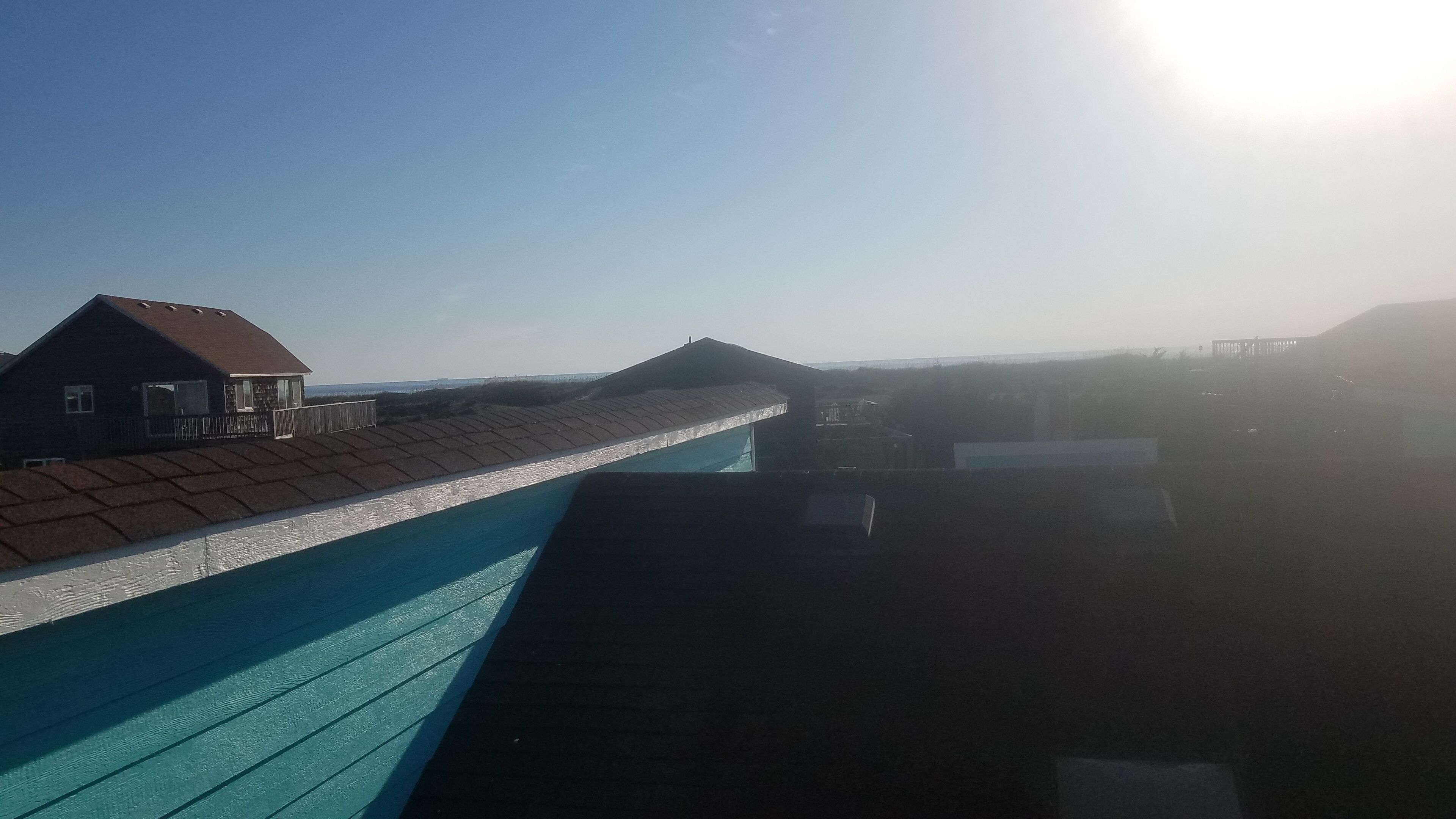 A swimming pool with a tiled deck and a house in the background.