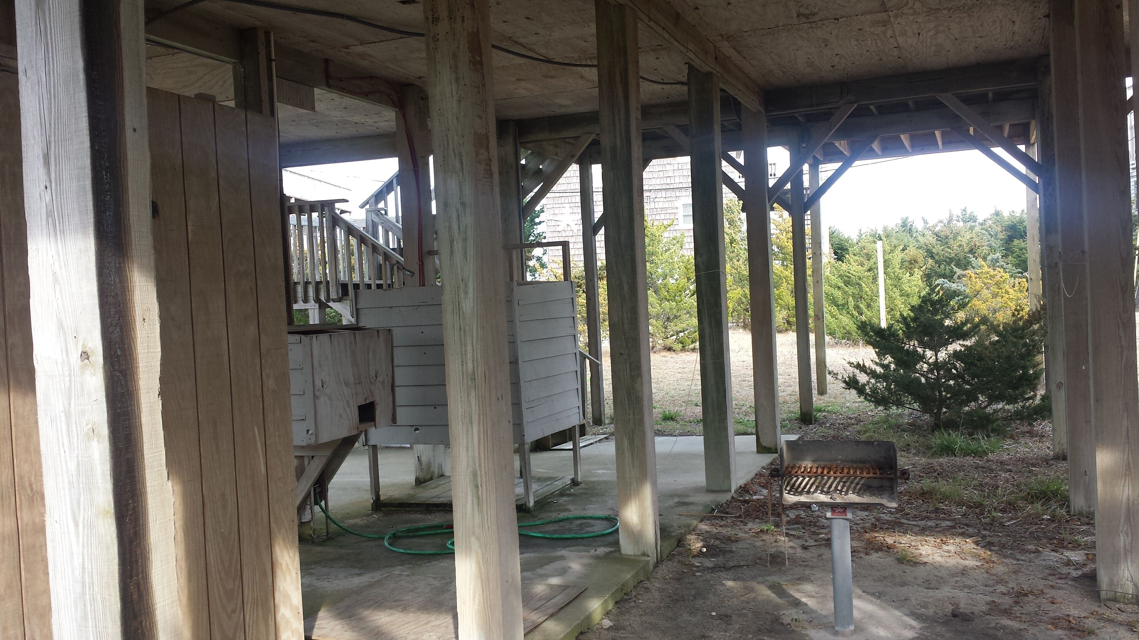 Une véranda en bois avec un banc en métal, un tuyau d’arrosage et un petit panneau.