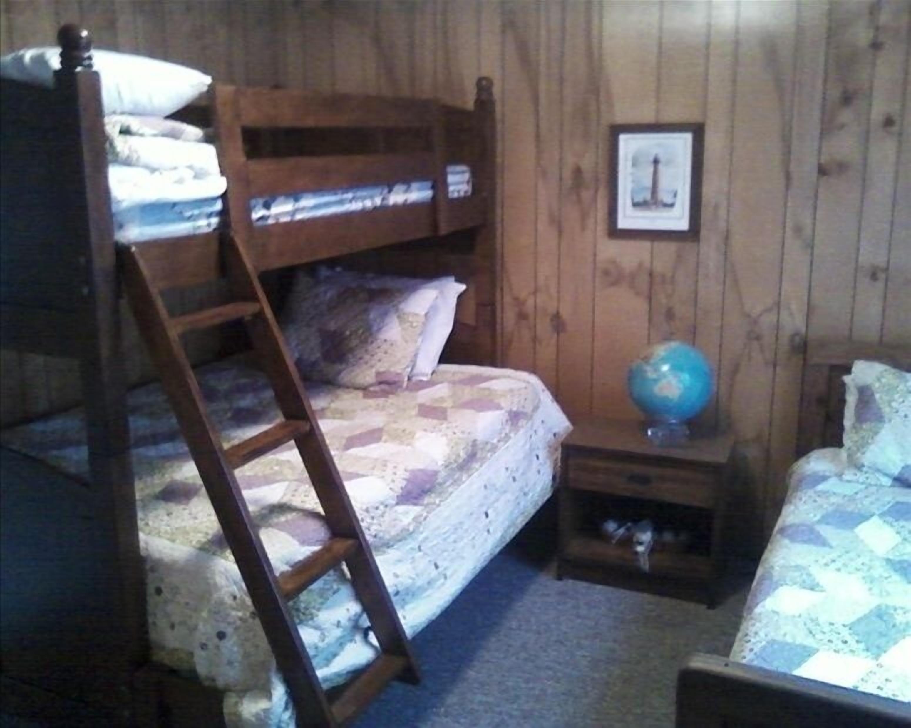 A bunk bed room with a ladder, a globe, and a framed picture on the wall.
