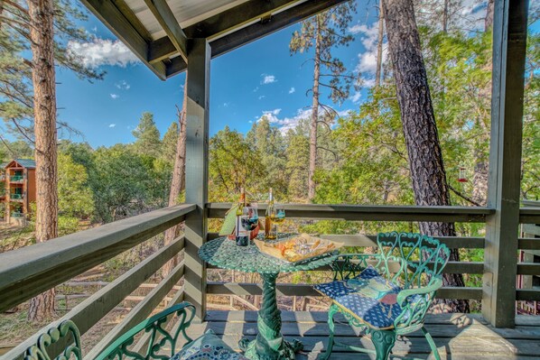 Une terrasse en bois avec une table et des chaises, entourée d’arbres.