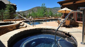 A hot tub with stone steps and metal railings, surrounded by outdoor seating and a mountain view. - Beaver Creek Landing 206 | 3BR Ski-In/Ski-Out, Summer AC (Beaver Creek)