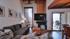 Una sala de estar con sofá, una mesa de centro de madera, chimenea y televisor.