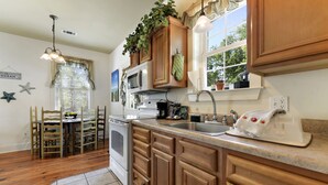 A kitchen with wooden cabinets, a microwave, a dishwasher, and a sink. - Quaint Cottage, Walk to Beach and Old Town Bay St. Louis (Bay St Louis)