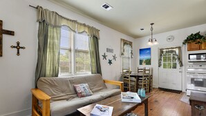 A cozy living room with a sofa, coffee table, and dining area. - Quaint Cottage, Walk to Beach and Old Town Bay St. Louis (Bay St Louis)