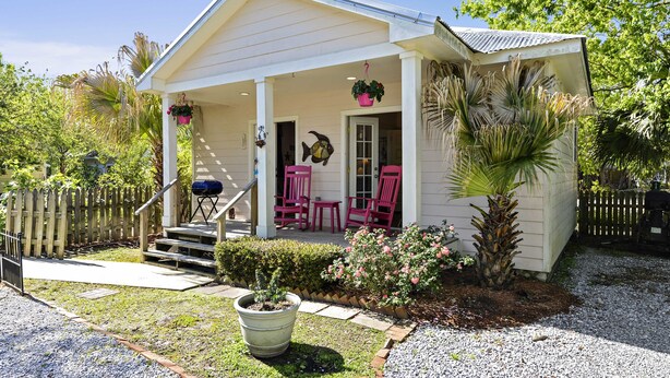 A house with a porch, steps, and a small garden area with plants and a potted plant. - Quaint Cottage, Walk to Beach and Old Town Bay St. Louis (Bay St Louis)