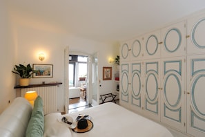 A bedroom with a bed, a nightstand, a lamp, a potted plant, and a wardrobe with circular designs.