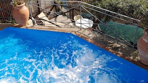 Una piscina con vistas a un pueblo costero y viñedos en terrazas.
