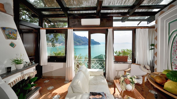 Una habitación acogedora con sofá, una mesa con un jarrón de flores y vista al mar.