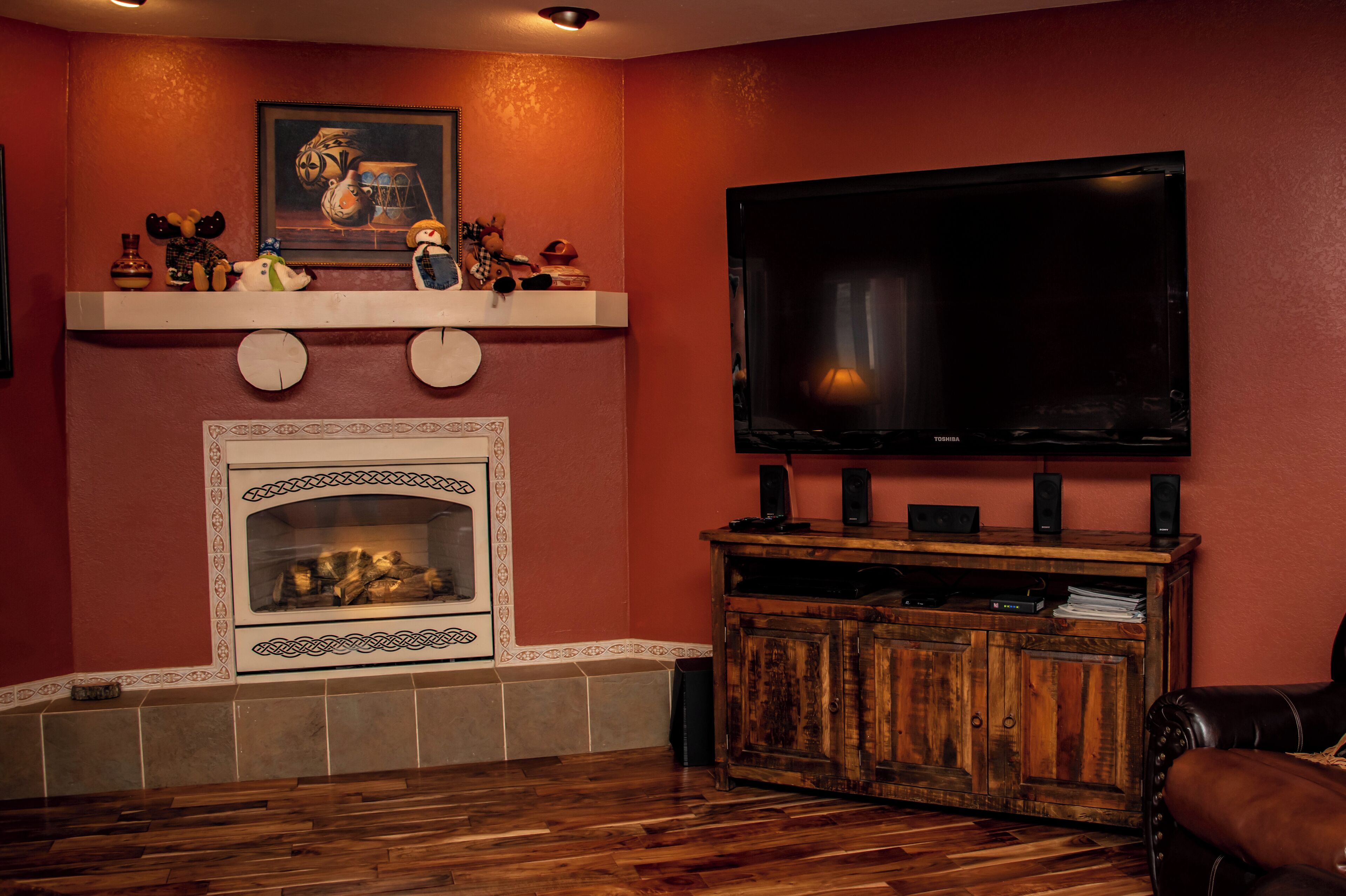 A living room with a fireplace, a mounted TV, and a wooden cabinet.