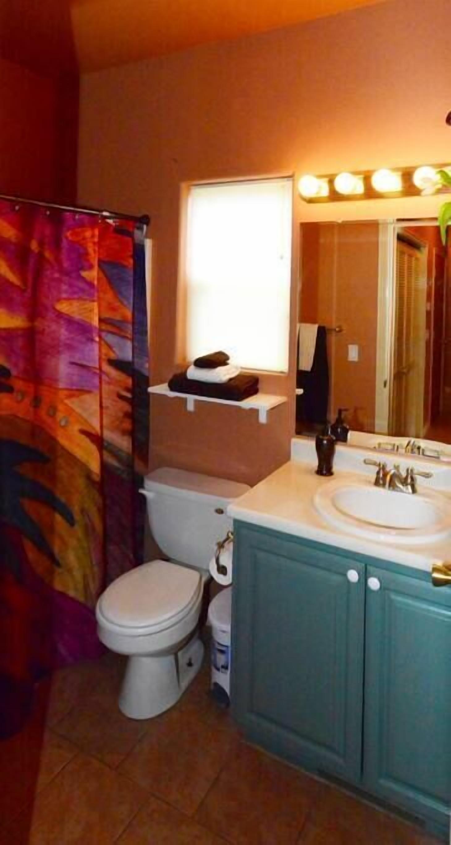 A bathroom with a white toilet, a sink with a mirror, and a shower curtain.