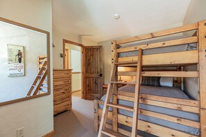 A room with a bunk bed, wooden dresser, and a ladder.