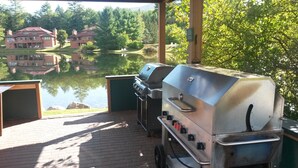 A covered outdoor area with a grill, a pond, and a view of a building across the water. - 
Deer Park 2BR Top Floor Quiet End Unit with AC/Wi-Fi/50" 4K TV Near Beach/Pool (North Woodstock)