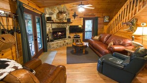A cozy cabin interior with a stone fireplace, leather furniture, and a television. - ROMANTIC TROUT FISHING CABIN - WiFi, HotTub FirePit, Blue Ridge, RiverMistCabin (Epworth)