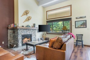 A living room with a stone fireplace, leather sofa, and a large window with a view.