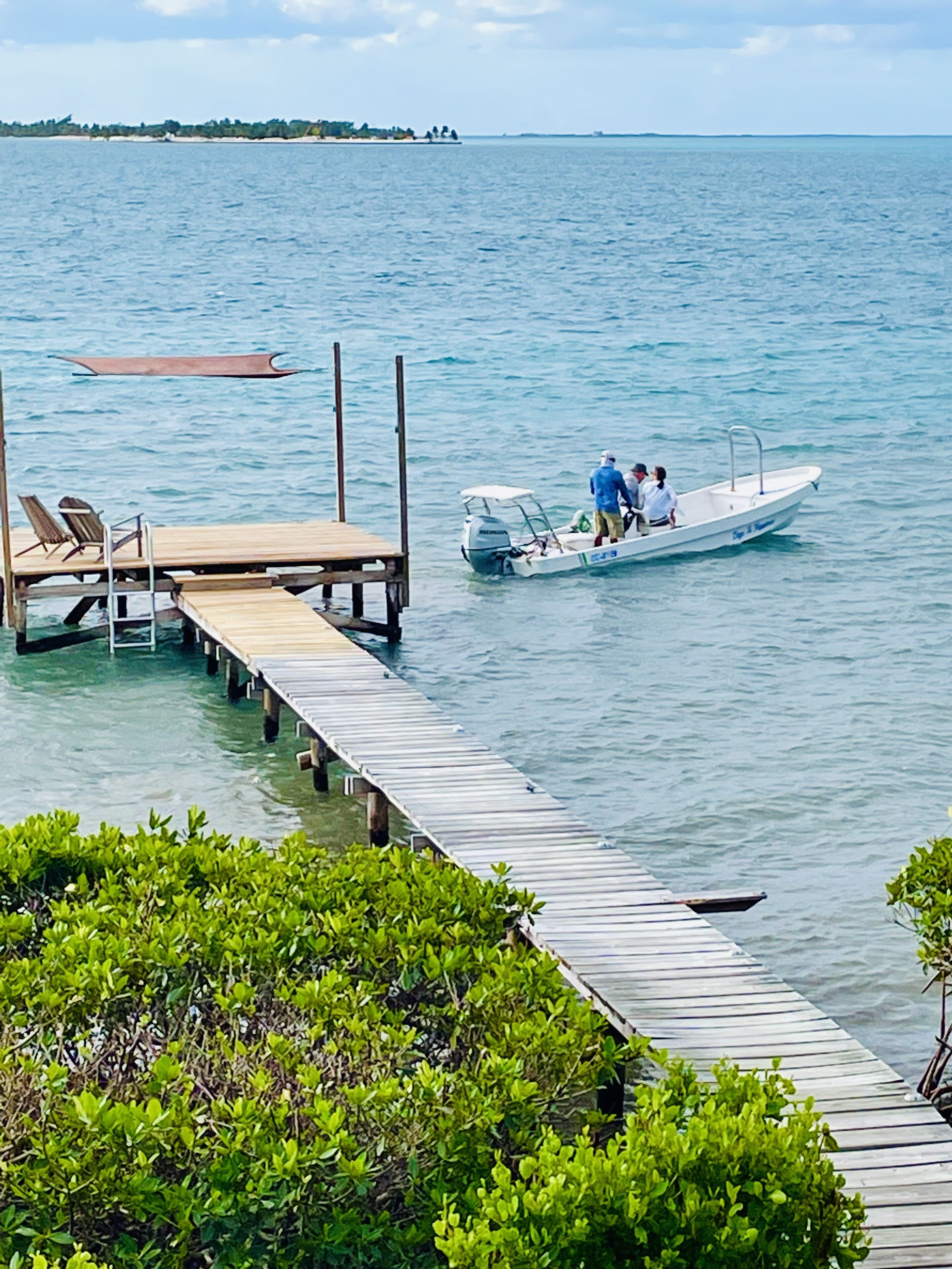 A wooden pier extending into calm waters with a small boat docked at the end.