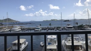 Een jachthaven met diverse boten aanmeren, een heldere lucht en heuvels in de verte.