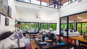 Un amplio salón con techo alto, ventanas grandes y ventilador de techo.
