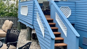 Ein blaues Haus mit einer überdachten Veranda, Sitzmöglichkeiten im Freien und einer Treppe.