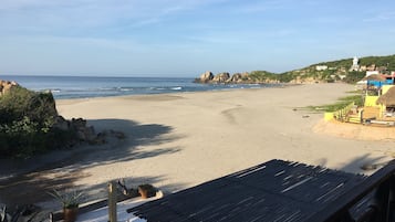 A beach with a wooden structure, a chair, and a potted plant.