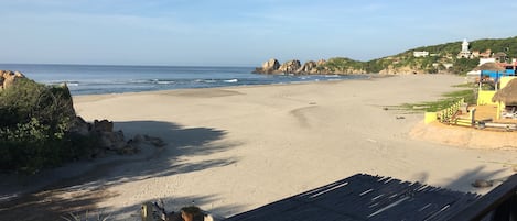 A beach with a wooden structure, a chair, and a potted plant.