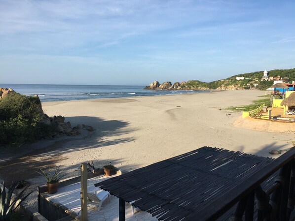 Ein Strand mit einer Holzkonstruktion, einem Stuhl und einem Blumentopf.