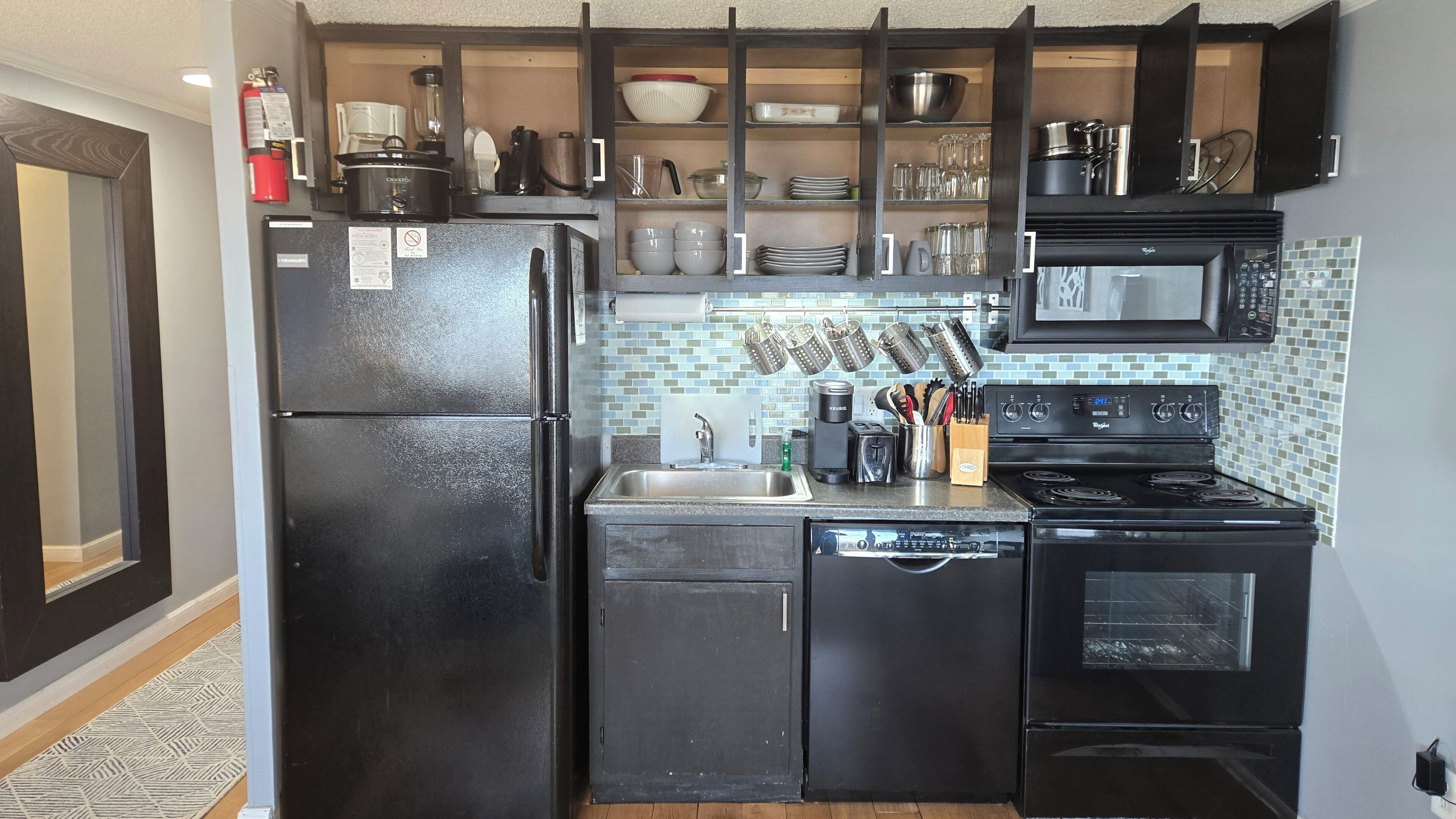 A compact kitchen with a refrigerator, stove, microwave, and sink.