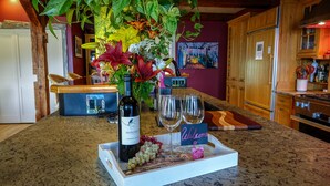 Una encimera de cocina con una botella de vino, dos vasos y un cartel de bienvenida.