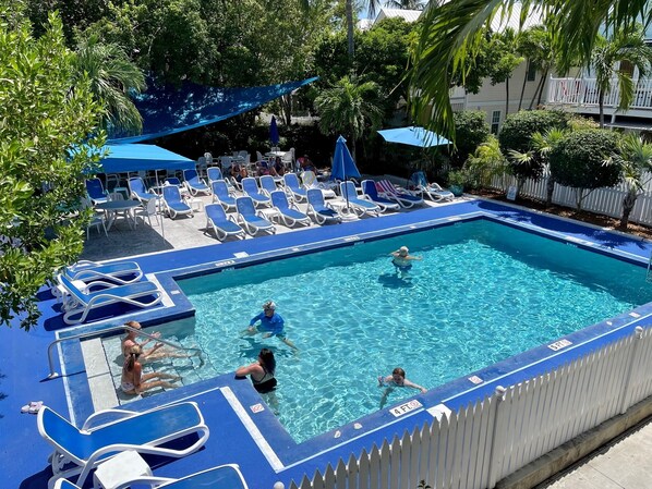 A swimming pool with blue water, surrounded by lounge chairs and umbrellas.