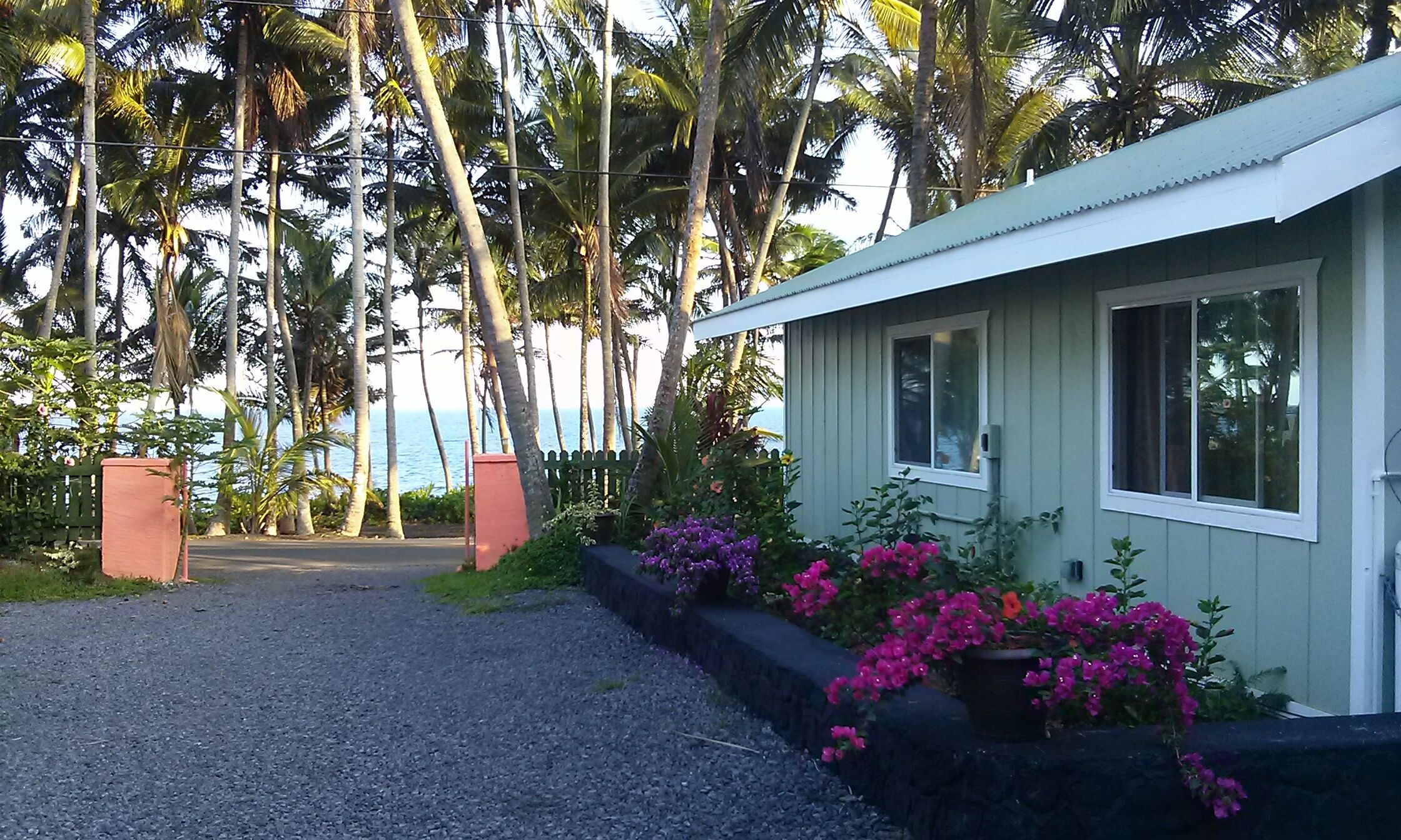 A small, single-story building with a gravel driveway leading to a gated entrance.